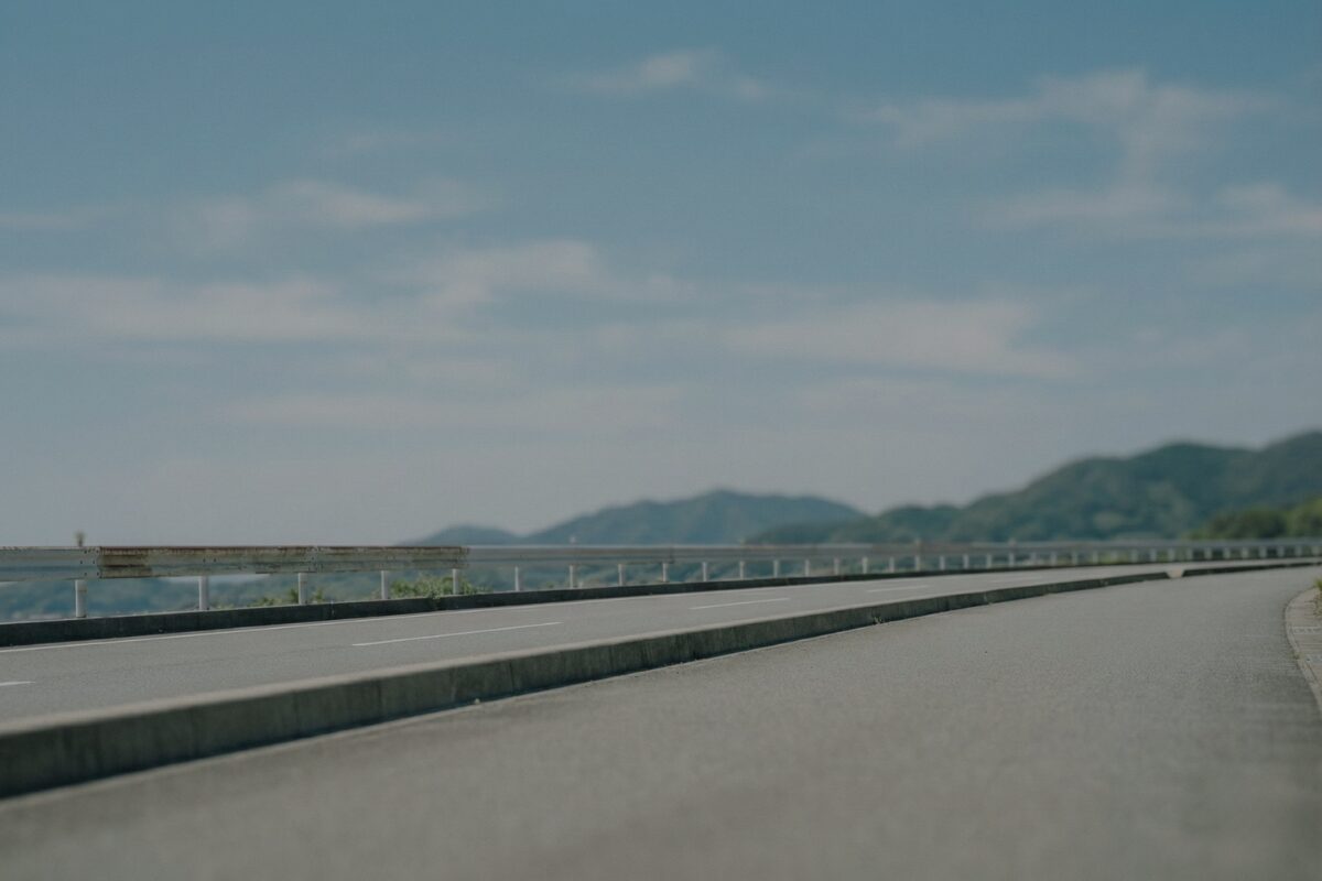 地域の道路風景と青空。移動と安全を支える企業の姿勢を表現したイメージ