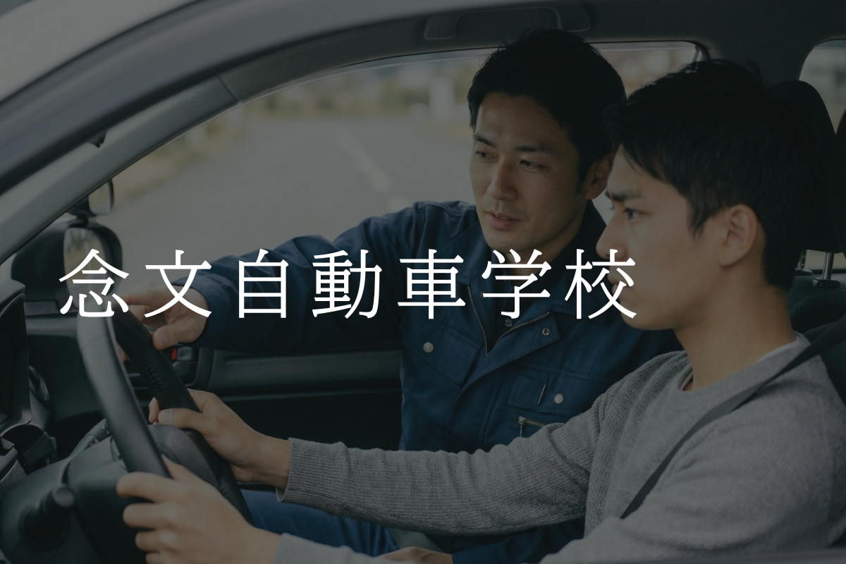 日本人教官が中国人教習生に対して車内で運転指導を行っている自動車学校の教習風景